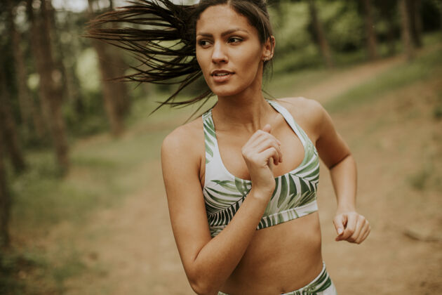 长跑在森林小道上跑步的年轻漂亮的健身女士跑步私人教练小径