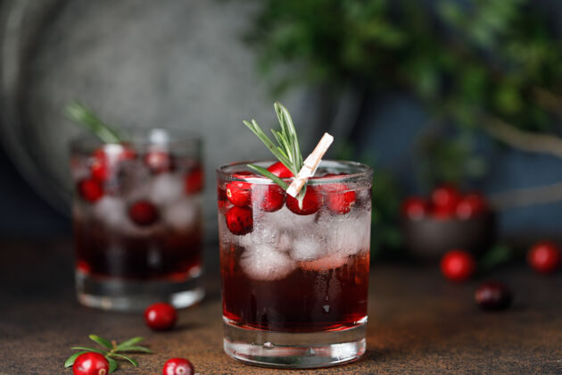 健康红莓鸡尾酒冰圣诞节红莓饮料在玻璃装饰糖和迷迭香圣诞节配料水