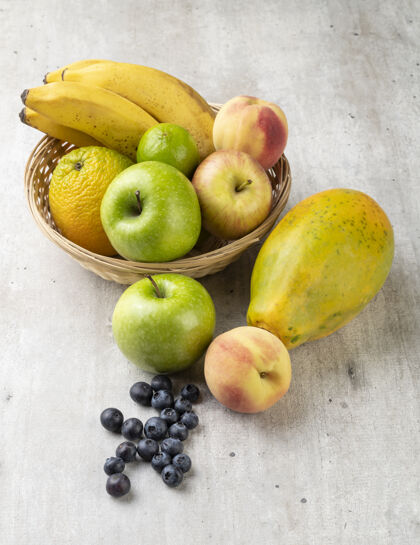 桃子在浅灰色的桌子上放一个篮子里的什锦水果有机香蕉热带
