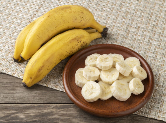 成熟把香蕉和切片放在木桌上的盘子里热带木头水果