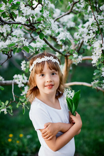 开花可爱的老花童站在花开的春天花园里的画像可爱服装夏天