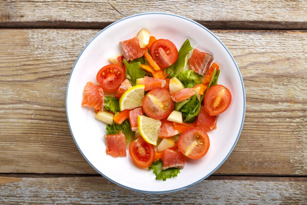 新鲜在木桌上的盘子里放上三文鱼和樱桃西红柿沙拉和蔬菜沙拉蔬菜樱桃番茄美食