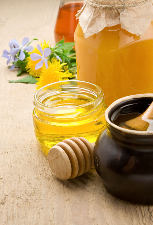 配料罐子里的蜂蜜和木头上的花滴玻璃勺