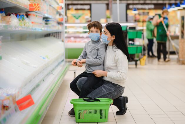 商业在冠状病毒流行或流感期间 一位母亲和她的小儿子戴着防护面罩在超市的画像爆发空文本空间客户流行病一起
