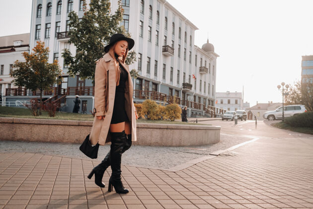 帽子一个穿着米色外套 戴着黑帽子的时髦年轻女子街头女人的街道时尚.秋季服装.城市风格时尚衣服手提包