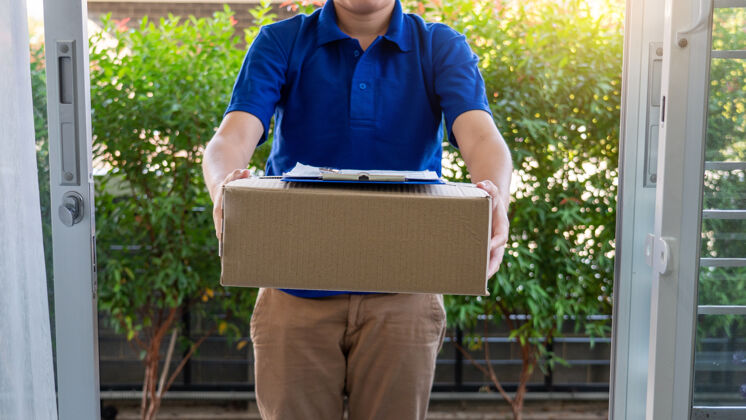 男人快递员检查或拿着纸板包裹快递给客户送货工业盒子