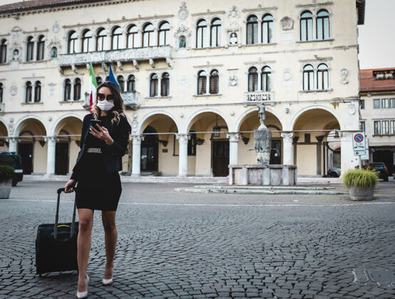 户外带着旅行箱的女商人带着防毒面具在城市里行走防护面具女士