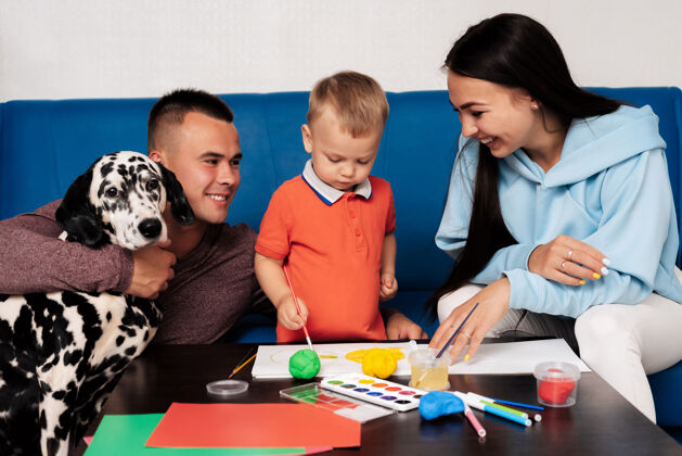 年轻快乐的家庭和一只达尔马提亚狗都在家里从事创意工作 玩得开心教学幼儿园生活