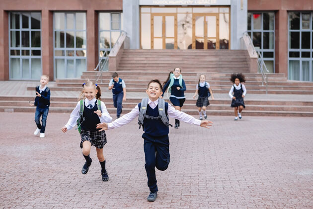 年一群穿着制服的小学生从学校的楼梯上跑下来小学生教育乐趣