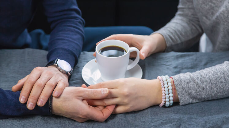 浪漫一男一女端着一杯咖啡坐在桌边浪漫女人情侣