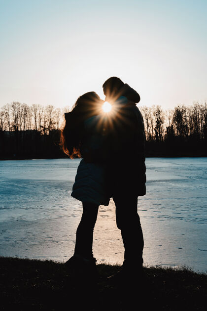 一起一对可爱的情侣的剪影映衬着公园里的湖水和夜空情人浪漫自由