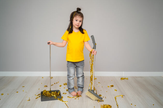 童年小女孩儿用扫帚打扫客厅家悲伤拿着勺子的女孩搅打孩子跟在他后面清理垃圾一个小女孩放假后打扫房子整洁房子生活