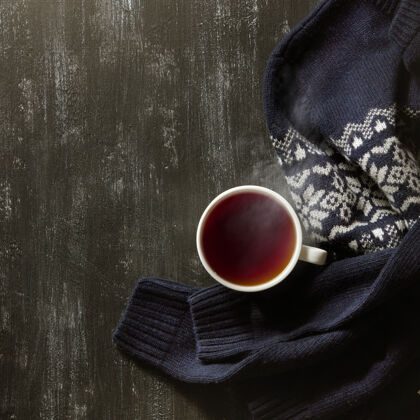 早餐舒适的冬季家居背景 一杯热茶和温暖的针织毛衣放在红桌上秋天芳香上衣