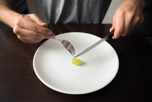 自然手拿刀叉放在盘子上 白盘子上放着绿葡萄素食者餐具有机