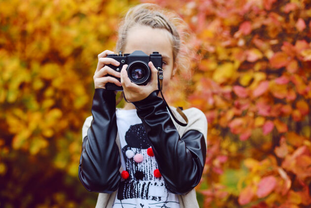 爱好十几岁的女孩用旧相机拍照休闲毛衣枫叶