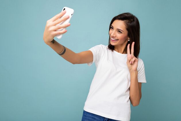 社交媒体美丽的微笑快乐的年轻女子穿着休闲白色t恤隔离墙流流行名人