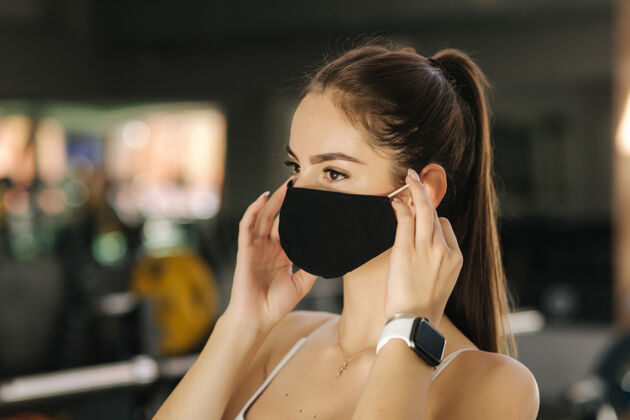 运动戴着黑色面罩的女运动员在体育馆的运动间隙休息健身房保护流行病