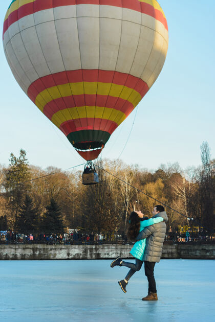 场景新娘和新郎在冰冻的湖面和城市公园里飞行的气球的背景下地质培训剪影