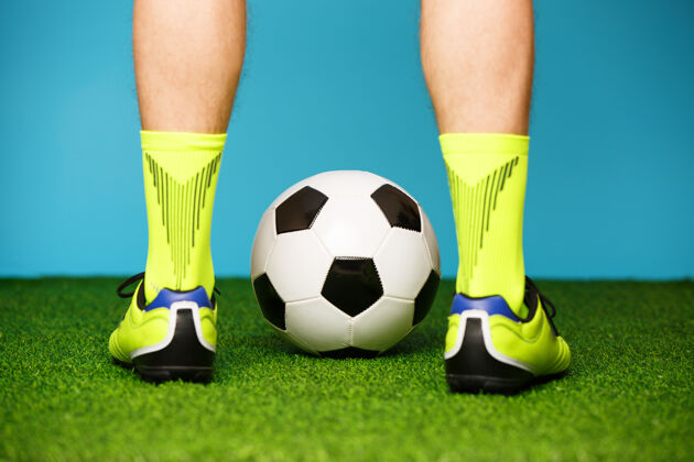 目标在绿草和蓝色背景上拿球的足球运动员冠军赢家比赛