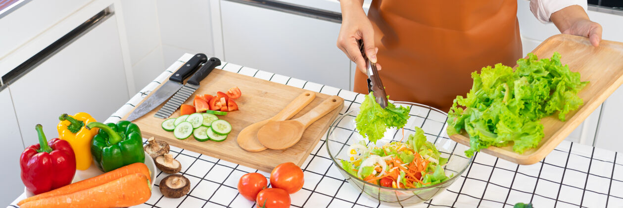 吃女人在准备健康食品蔬菜沙拉的过程中年轻成人饮食