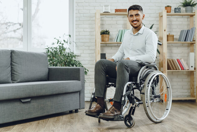 保险坐在轮椅上快乐微笑的年轻人呆在家里室内男性残疾