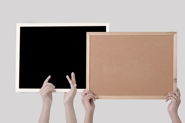 黑板一只手拿着一块棕色软木板 黑板隔着一堵白色的墙文具办公室板子