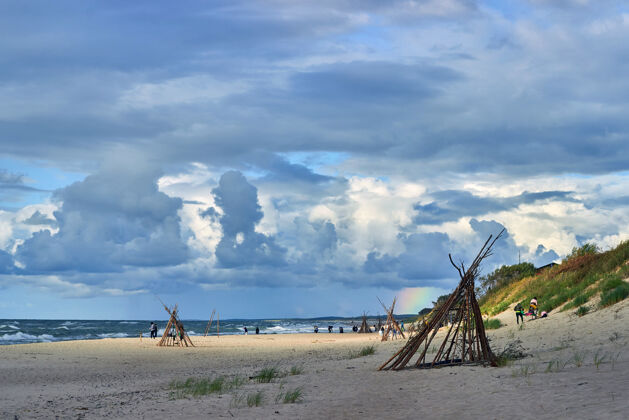 多云美丽的多云的天空和彩虹在沙滩上威格瓦姆斯人在海边休息沙漠沙滩海岸