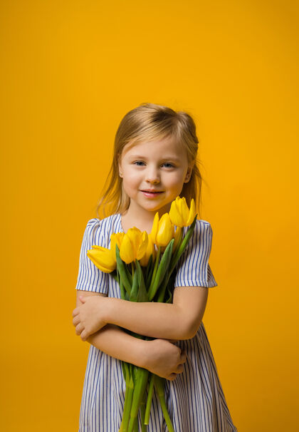 黄色郁金香一个穿着条纹连衣裙的快乐小女孩手里拿着一束黄色郁金香小年轻时尚