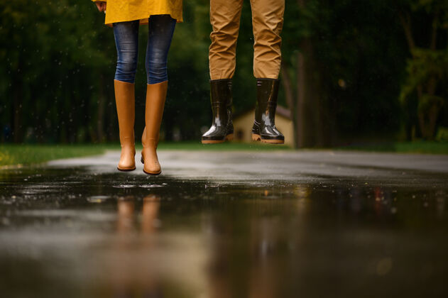 女人一对恋人跳进公园的水坑里 夏日多雨戴曼雨伞下的女人 散步路上的浪漫约会 小巷里的潮湿天气男人情人户外