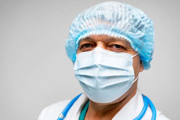 医疗戴着面罩站在灰色背景下的资深男医生男人外科医生面具