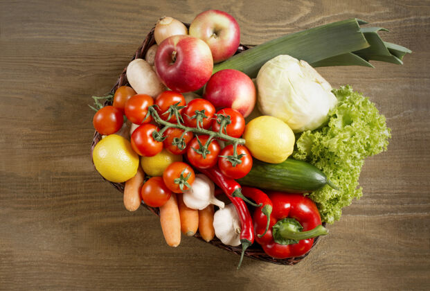 樱桃木制背景上柳条篮子里的一套蔬菜和水果的俯视图土豆产品套装木桌