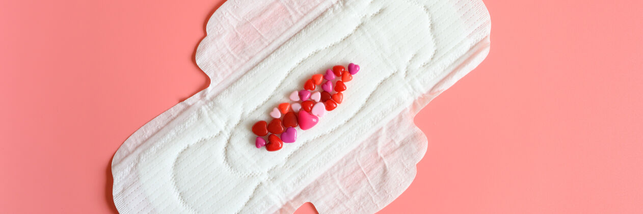 垫女性月经时用的卫生巾或餐巾纸为正常分泌的大量分泌物 用红色珠子做成心形的仿血特写自然餐巾