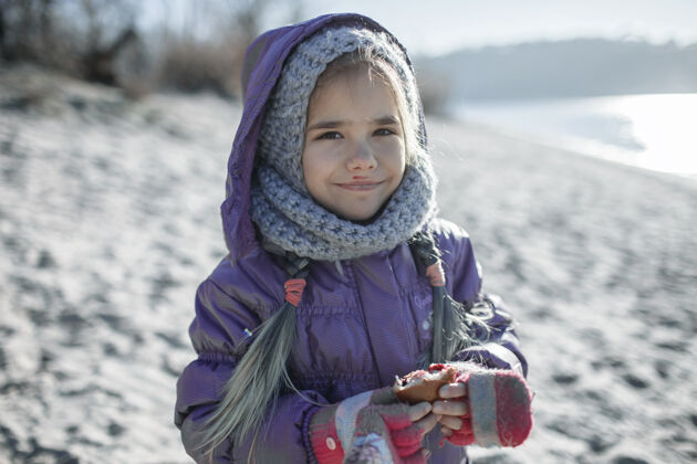 微笑冬天 孩子在沙滩上散步 寒冷的温度和阳光明媚的日子快乐孩子编织帽子
