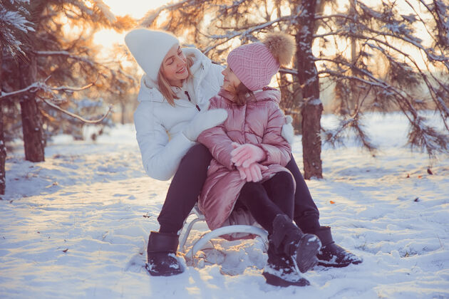 快乐妈妈和女儿在冬季公园玩得很开心童年户外女人