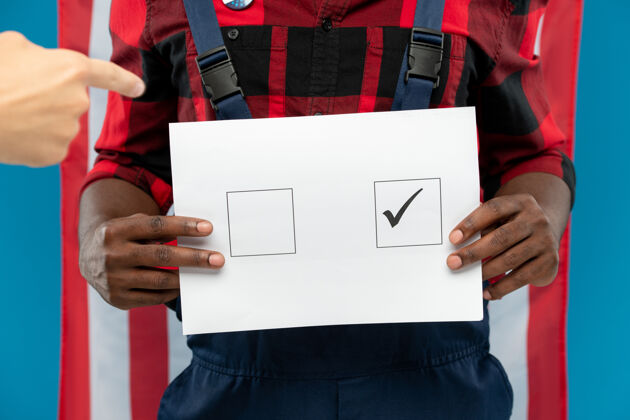 投票年轻的黑人修理工站在美国国旗前 手里拿着方格上打勾的选票标志信息人手