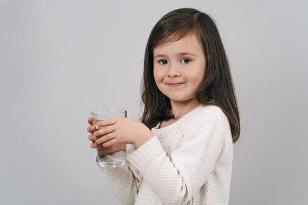 净化孩子喝玻璃杯里的水一个黑发女孩拿着一杯水水水黑发女人过着健康的生活新鲜清晰治疗