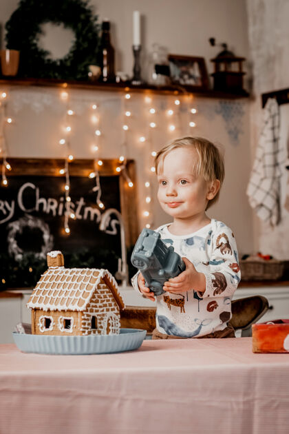 小小男孩站在装饰着圣诞花环和装饰品的厨房里 一边玩着新年礼物男孩灯年轻