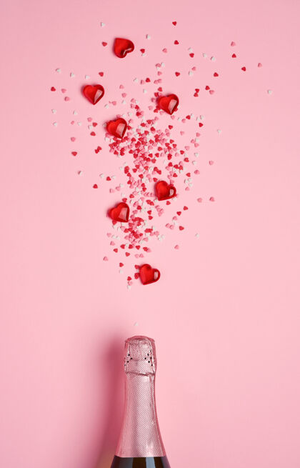 酒杯香槟酒瓶上有红色心形的五彩纸屑和粉红色的装饰性心形图案背景情人节礼物天概念.top查看 复制空间饮料活动叮当