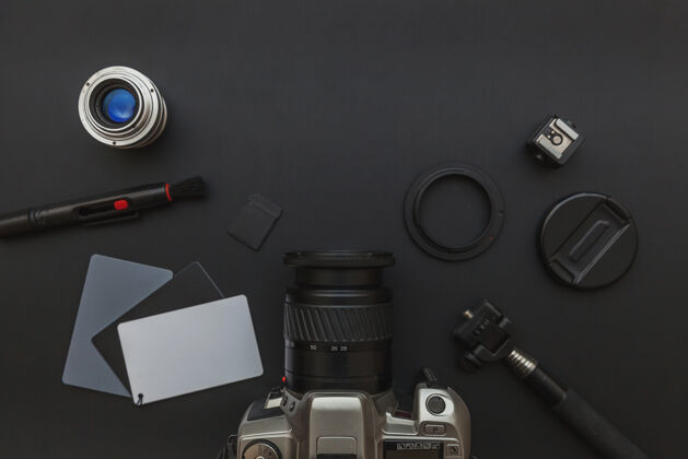 黑暗摄影师工作场所配有单反相机系统 相机清洁套件 镜头和相机配件 背景为深黑色桌面技术记录模拟