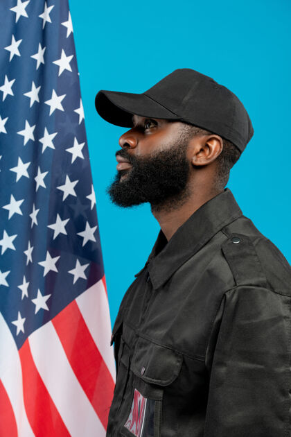 制服侧视图年轻的留着胡须的非洲裔美国男性保安在黑色制服和帽子站在反对星条旗投票国家地标