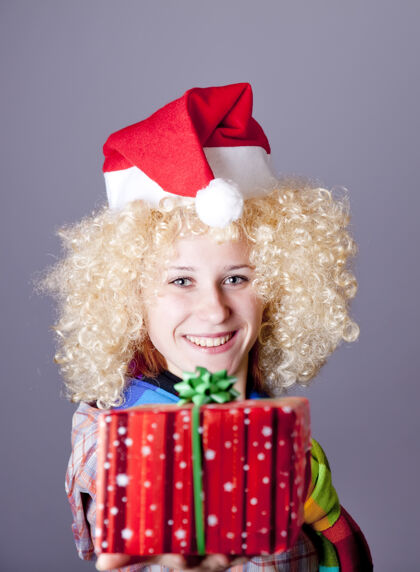 可爱戴着金色假发和圣诞帽的女孩秀礼品工作室射击女性礼物尼斯