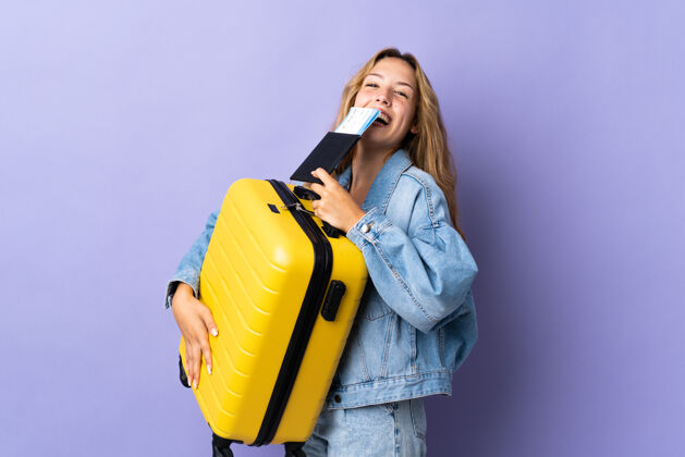 金发女郎年轻的金发女郎带着手提箱和护照在紫色的海滩上度假旅行女性设备