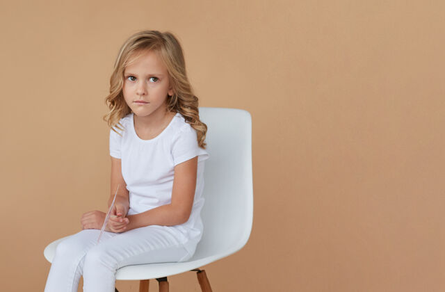 可爱正面特写 可爱的金发小女孩 穿着白色衣服 坐在椅子上时尚女孩工作室