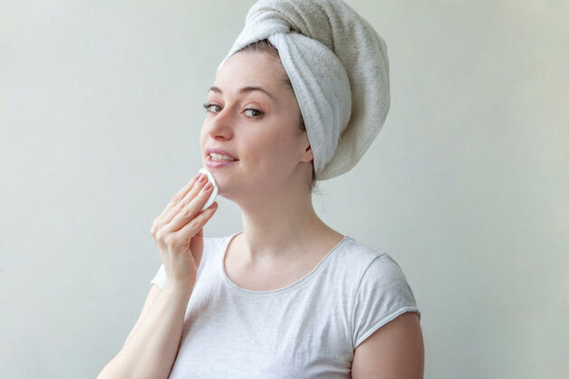 敏感头上戴着毛巾的微笑女人的美丽肖像 柔软健康的皮肤 用隔离在白色背景上的化妆棉卸妆水疗完美皮肤护理