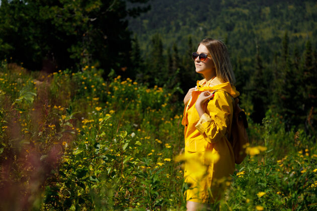 自然穿着黄色雨衣 背着背包的时尚潮人女人旅行者夜晚户外阿尔卑斯山