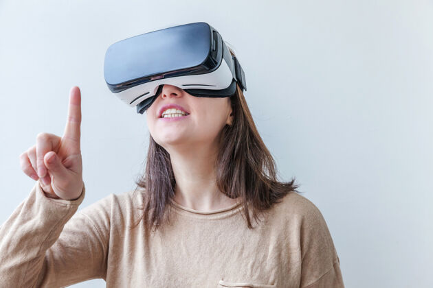 设备微笑的年轻女子戴着虚拟现实vr眼镜头盔耳机在白色背景上视觉想象模拟