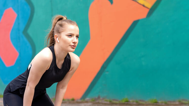 金发年轻专注的金发女子在户外训练后休息跑步 五彩背景瑜伽集中健康
