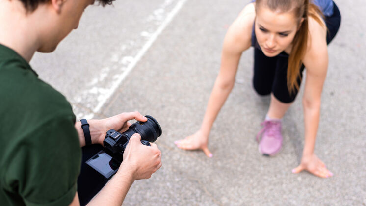 瑜伽摄影师拍摄的一个年轻的金发女子穿着运动服准备开始在户外训练 路手表身体伸展