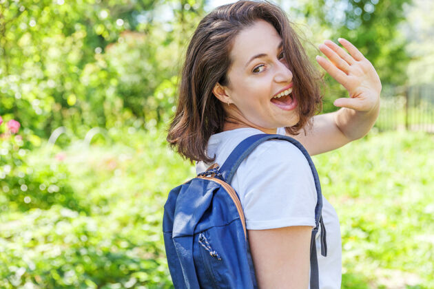 商务快乐积极的女学生 背着背包 在绿色公园的背景下微笑着秋天人公园