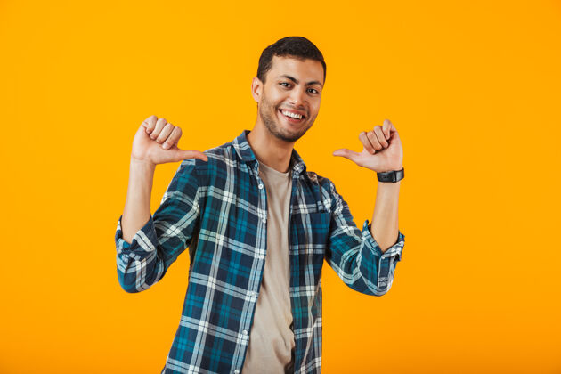 思考一个穿着格子衬衫的年轻人孤零零地站在橙色的墙上 指着自己欢乐男性年轻